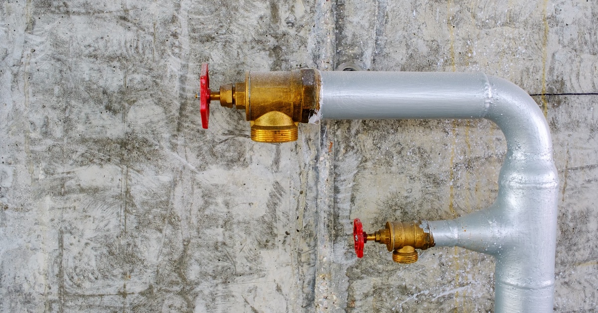 A close-up of two brass valves on a metal water pipe connected to an industrial extinguisher system.