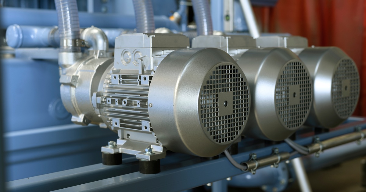 A close up of a vacuum pump station. There are three silver canisters attached to a light blue housing unit.