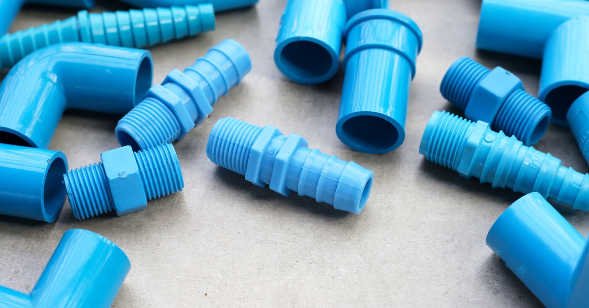 A collection of blue PVC pipe connections. The pipe connections are scattered next to each other across a gray table.