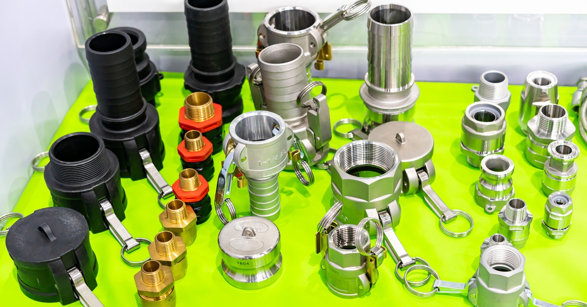 A series of camlock fittings in different materials and finishes. They are all set up on top of a green table.