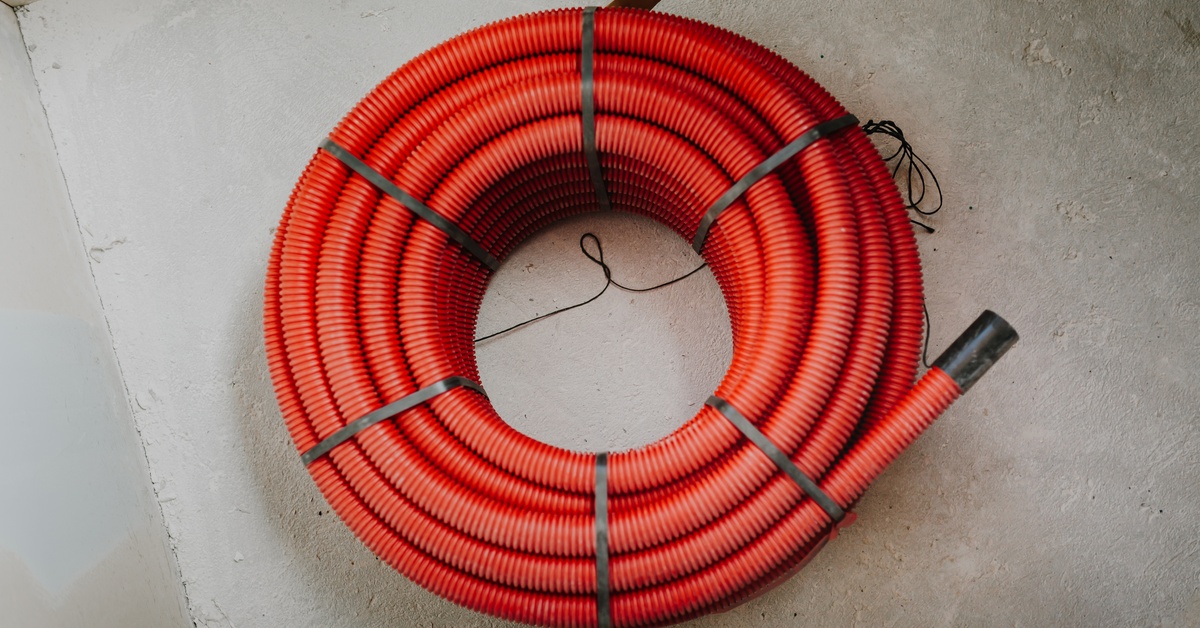 A coil of orange corrugated hose wrapped around on itself. The coil is held together by large black zip ties.