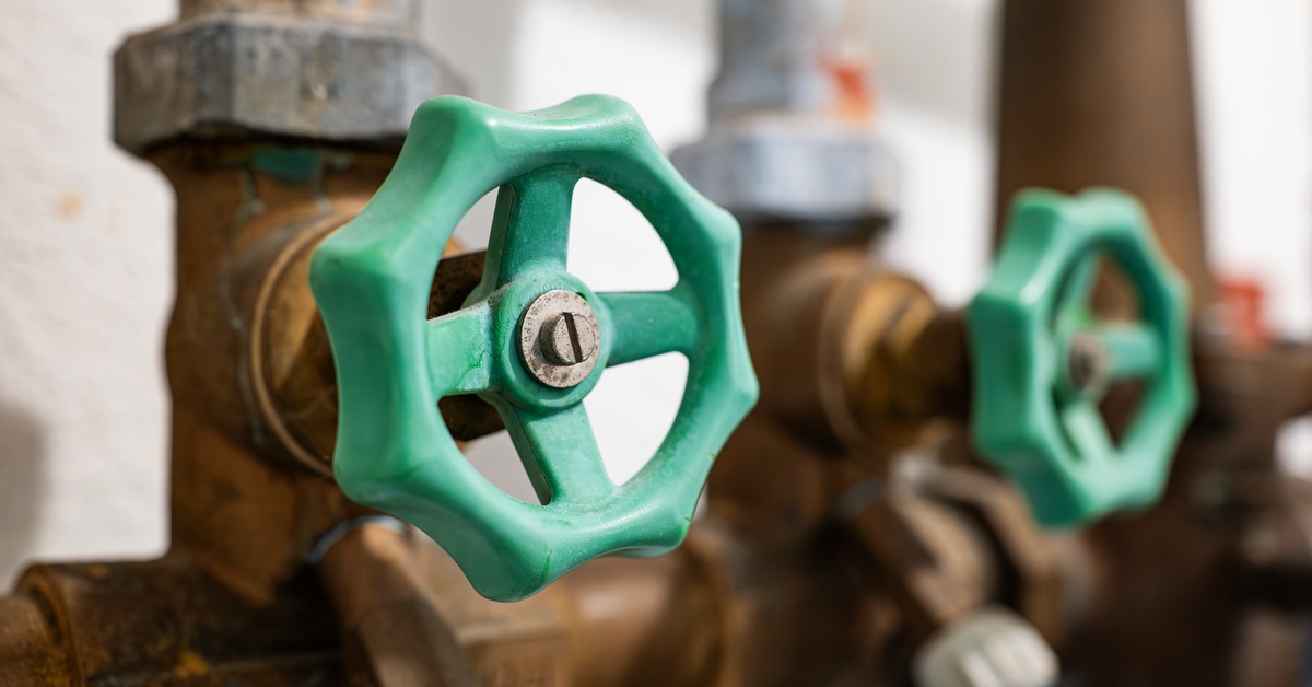 A closeup of small, brass, silicone-covered valves that are connected to a plumbing system inside of a home.