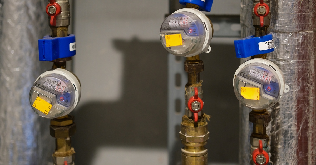 A closeup of an indoor plumbing system. there are three pipes with brass valves on them and small gauges.