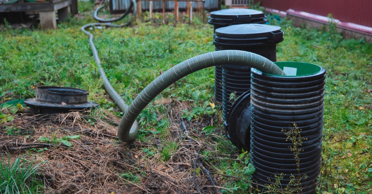 A long hose going into a service pipe for a septic tank. The hose is in the middle of pumping out sewage.