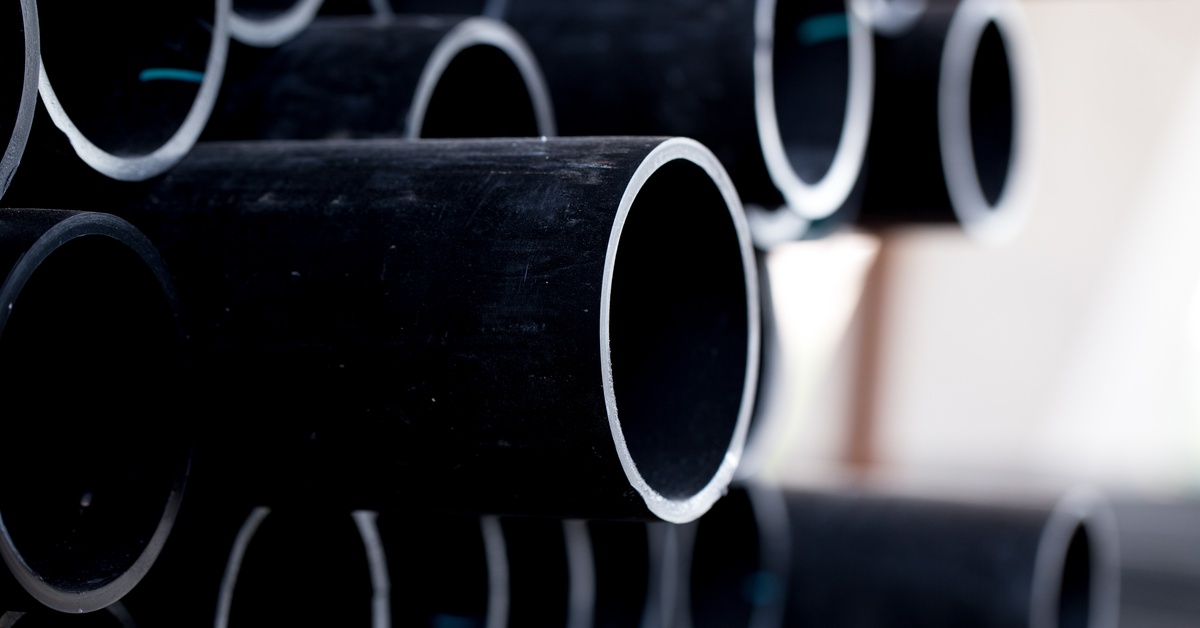 A close-up of a pipe of various black steep pipes sticking out of the pile at various lengths against a bright background.