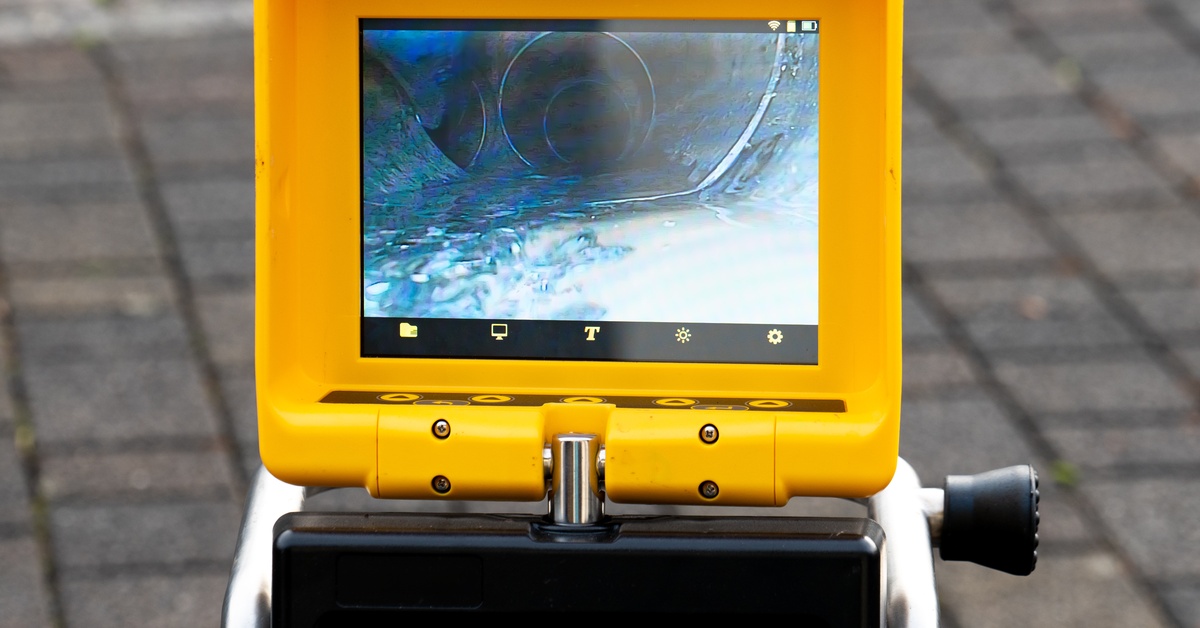 A close-up of a drain inspection camera monitor showing the layout of a large drainage system. A yellow frame outlines the feed.