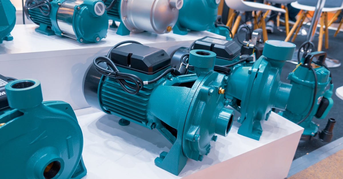 A number of teal water pumps are lined up on several levels of a white shelf. White seats are in the background.